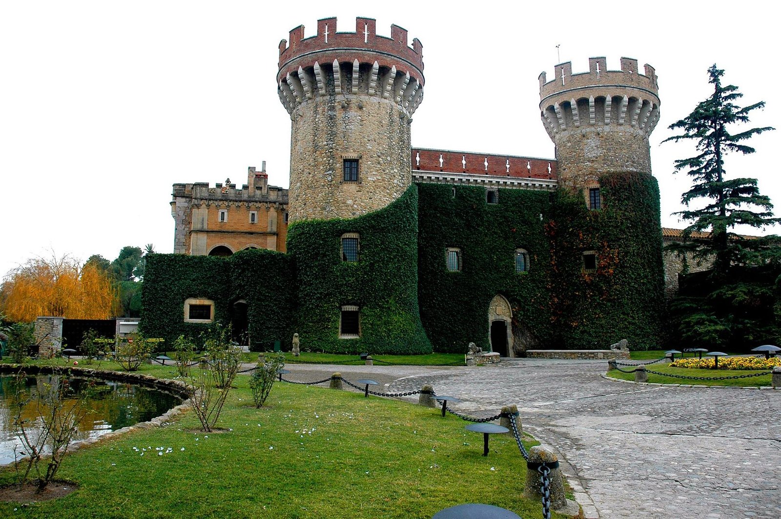 Façana del Castell de Peralada, amb les dues torres circulars i els murs coberts d'heura
